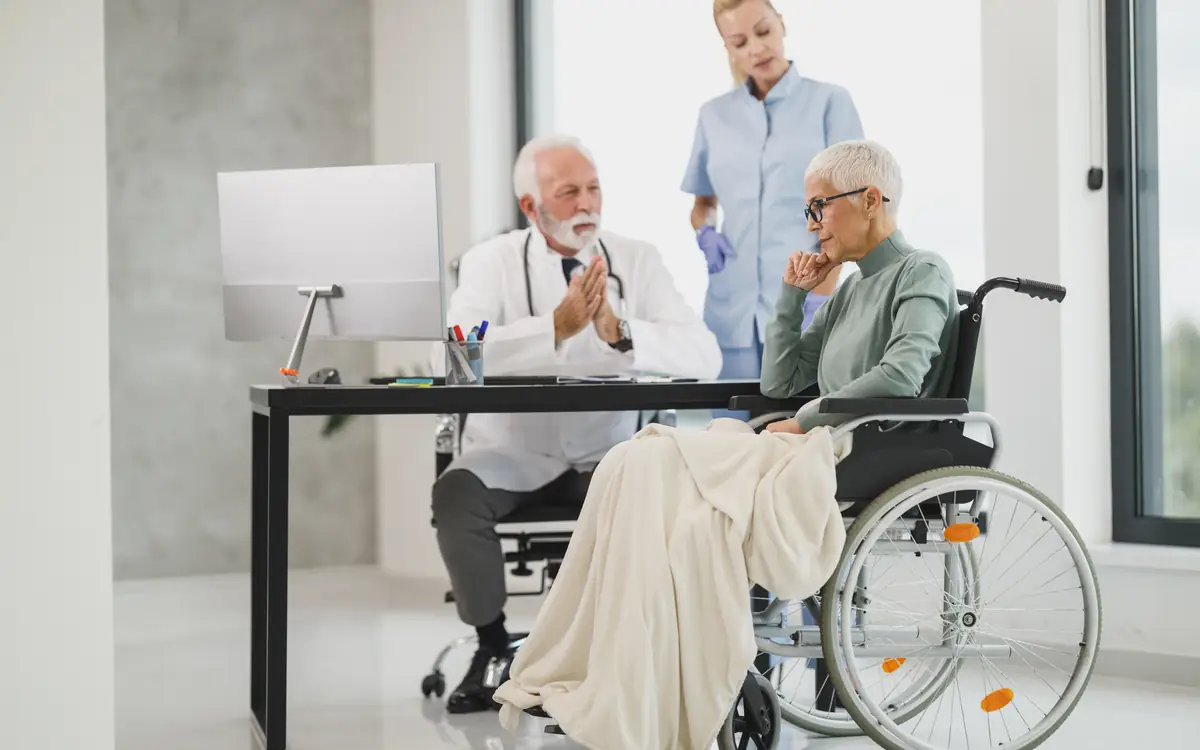 Person in a wheelchair in conversation with a healthcare worker