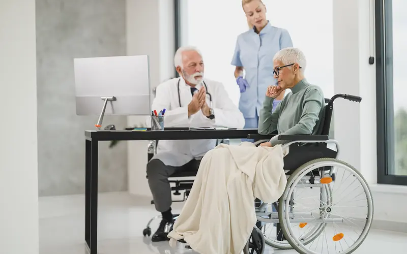 Person in a wheelchair in conversation with a healthcare worker