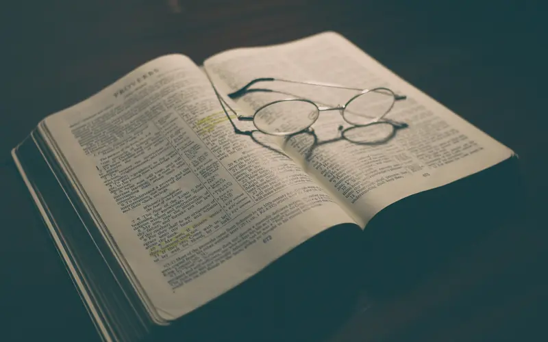 Open book with a pair of reading glasses resting on its pages