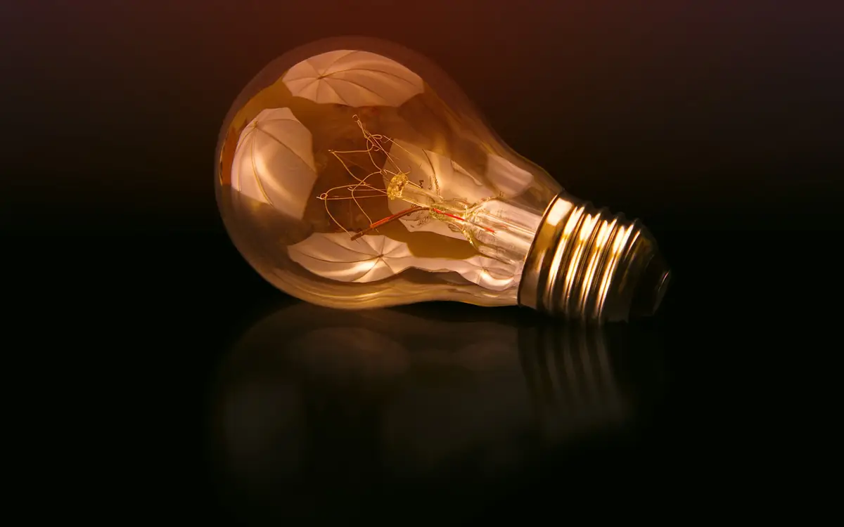 Glowing filament light bulb against a dark background
