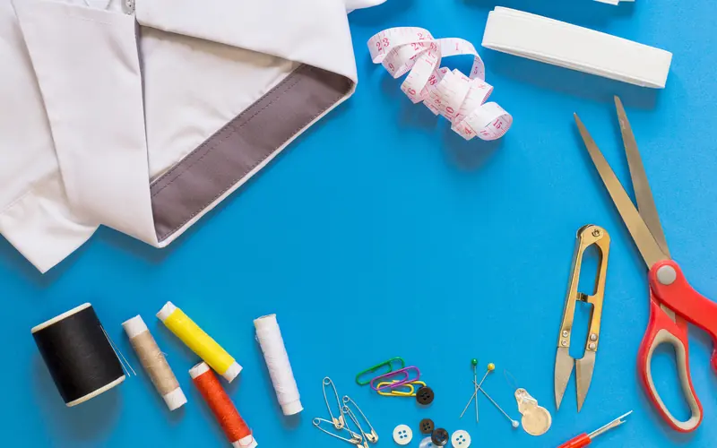 Tape measure, scissors, thread and sewing notions on a blue surface
