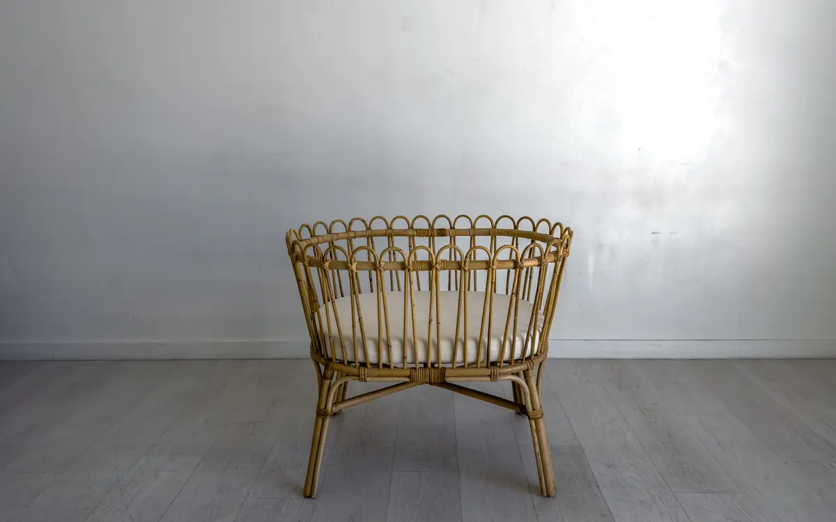 Wicker chair against a plain grey wall and floor
