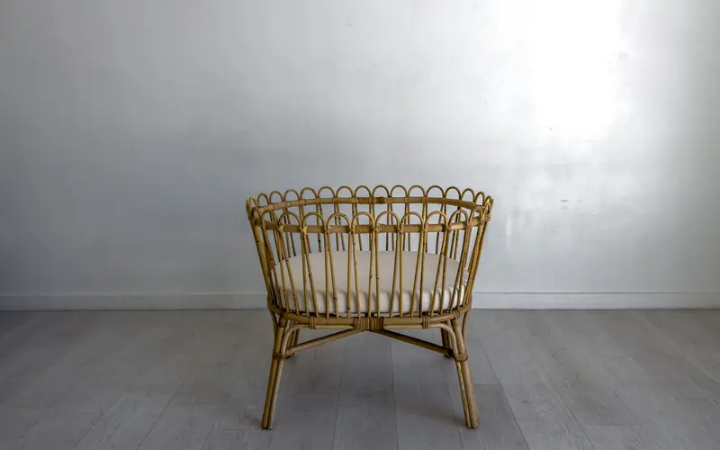 Wicker chair against a plain grey wall and floor