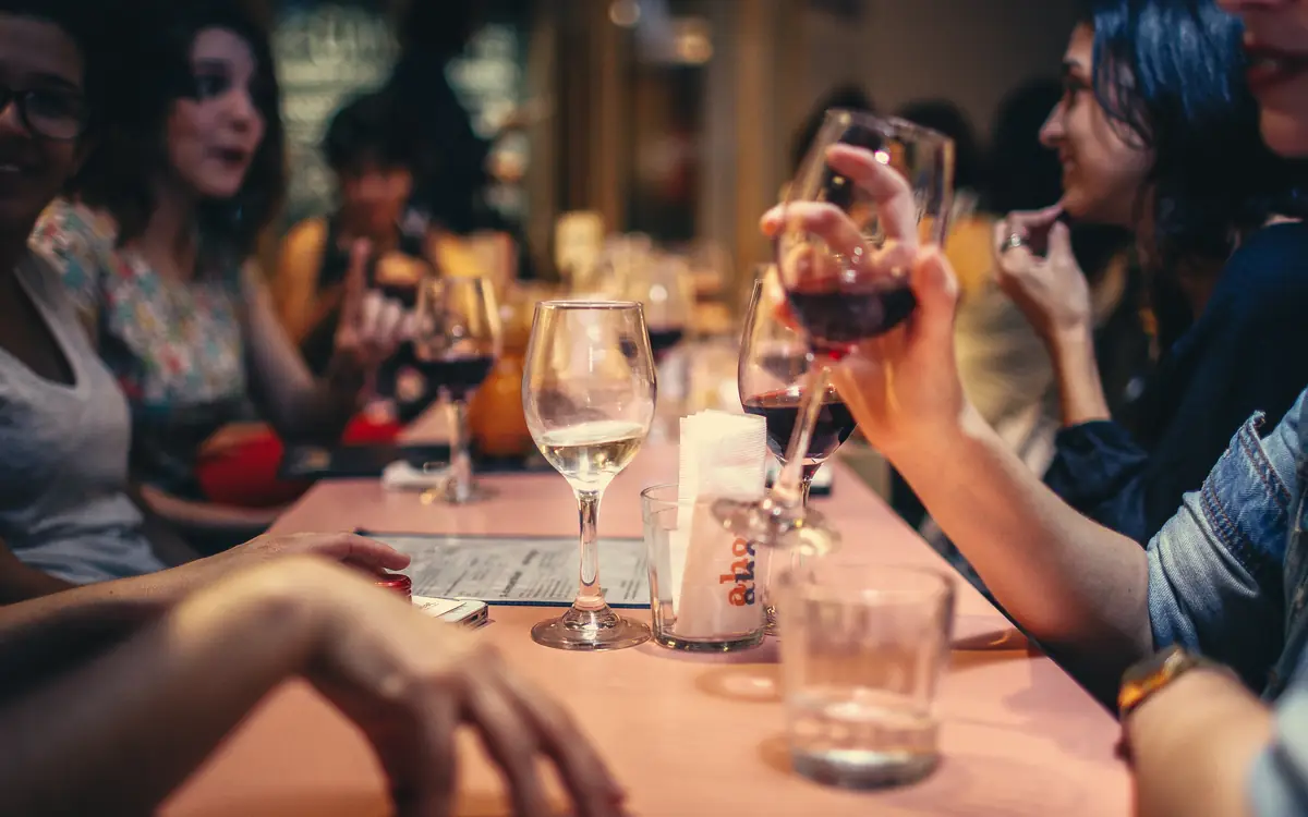 Group of friends sharing drinks and conversation around a restaurant table