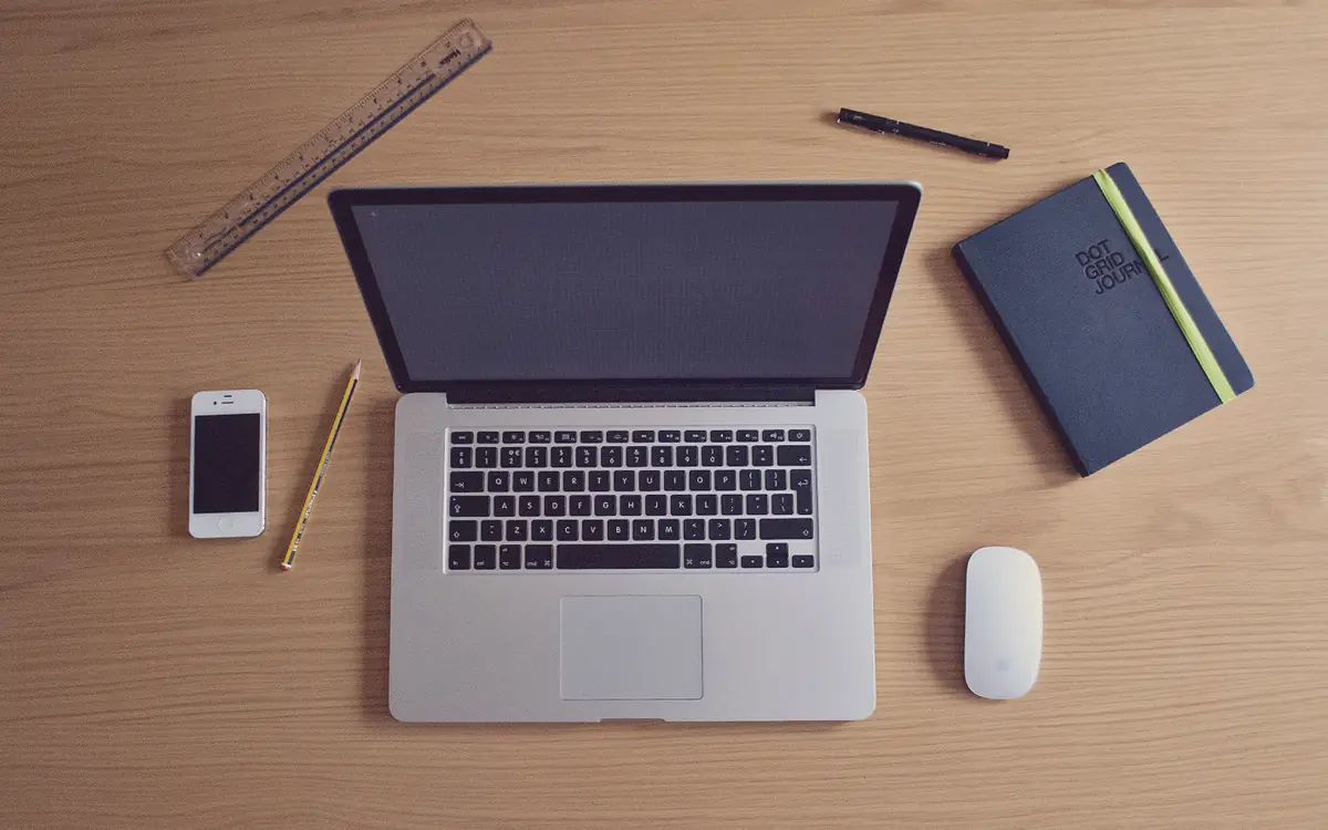 Overhead view of a laptop, notebook and phone on a wooden desk