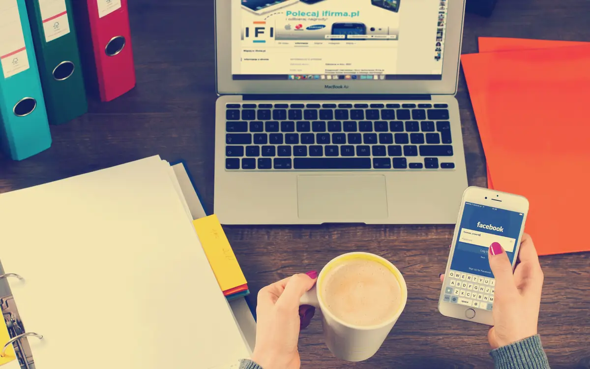 Desk with a laptop, coloured document folders, a phone and a cup of coffee