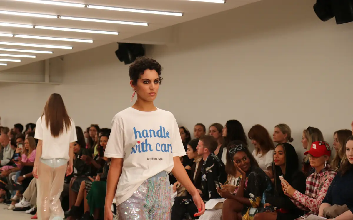 Model walking the catwalk at Roberta Einer's London Fashion Week show as the audience watches
