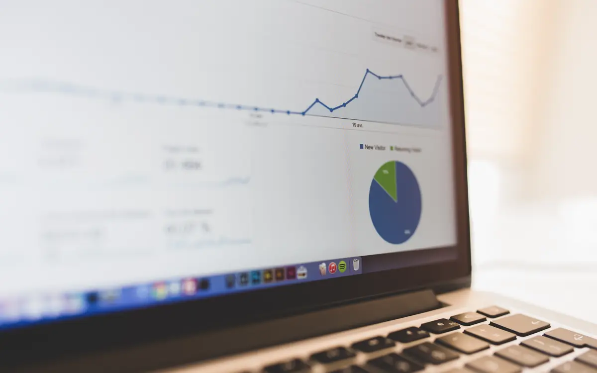 Laptop displaying analytics charts on a desk with a notebook