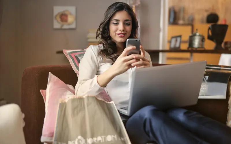 Smiling woman shopping online with a laptop and shopping bags