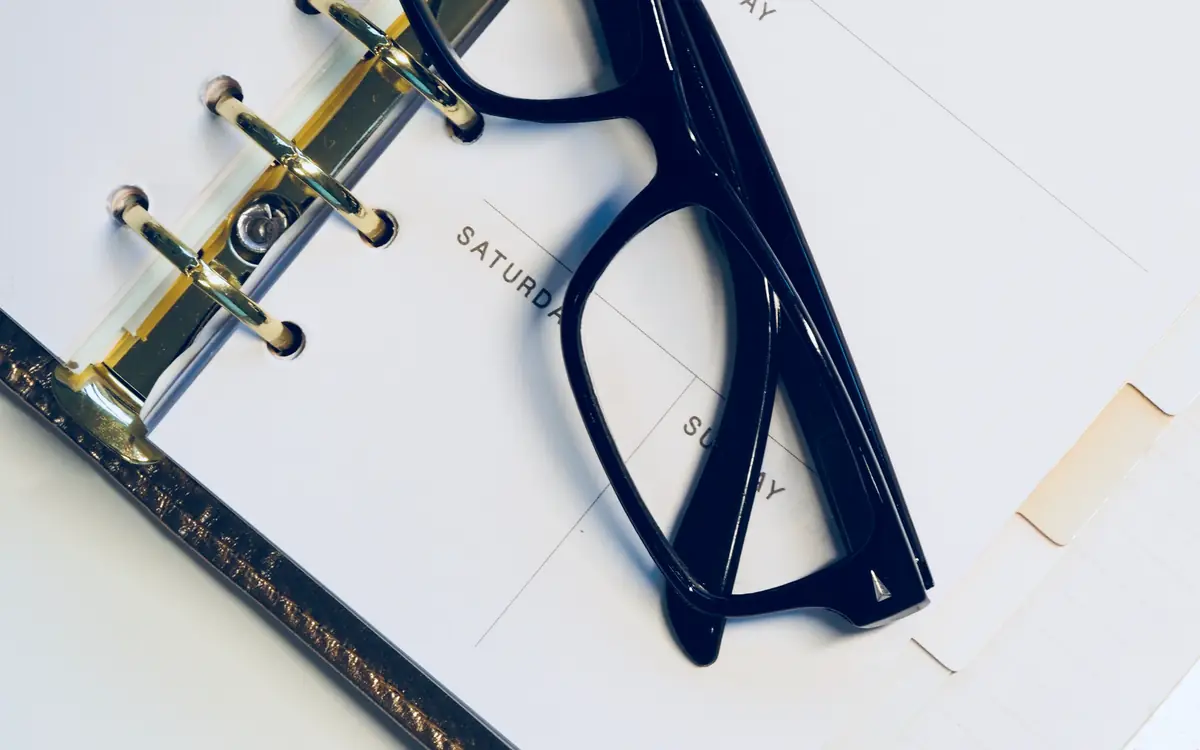 Ring-bound planner open beside a pair of dark-framed glasses