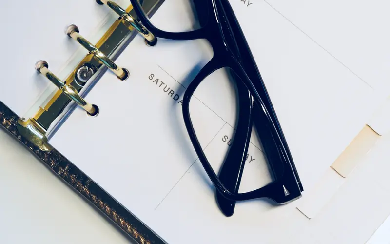 Ring-bound planner open beside a pair of dark-framed glasses