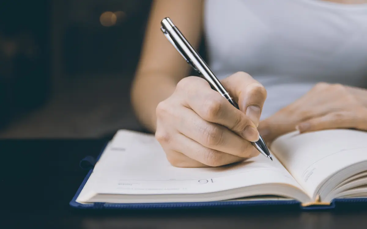 Woman writing in a diary with a pen