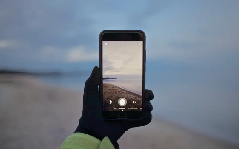 Hand holding a smartphone outdoors at dusk
