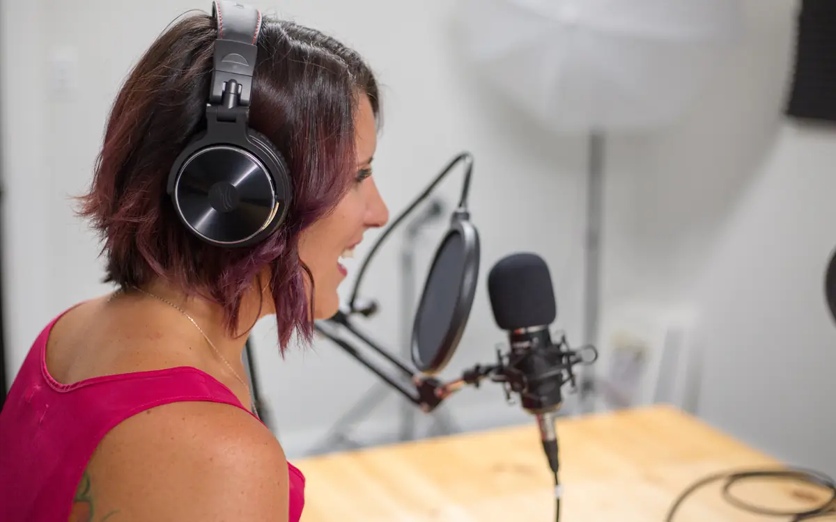 Woman wearing headphones speaking into a studio microphone