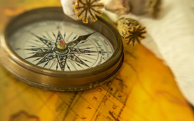 Antique brass compass lying on an old map