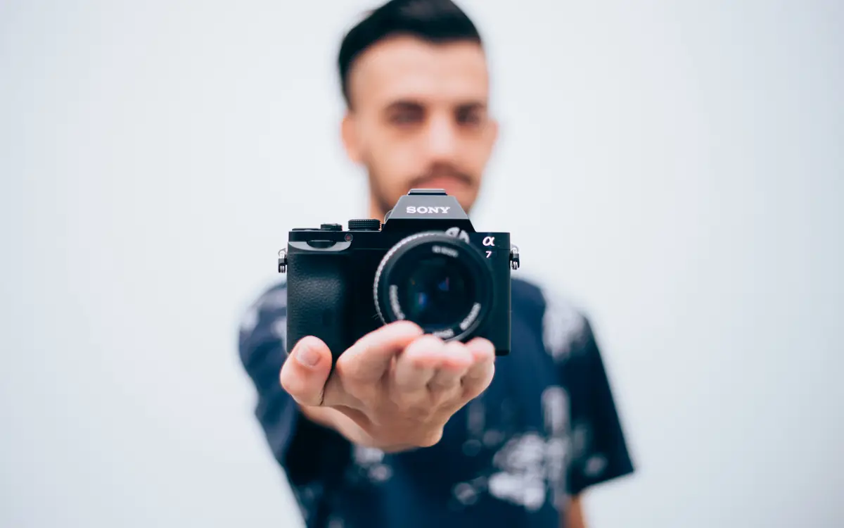Man holding a mirrorless camera towards the viewer