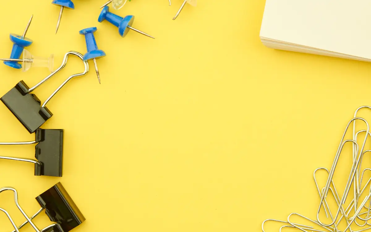 Push pins, paper clips and notes arranged on a yellow board