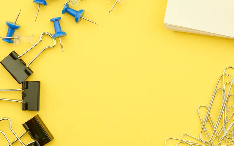 Push pins, paper clips and notes arranged on a yellow board