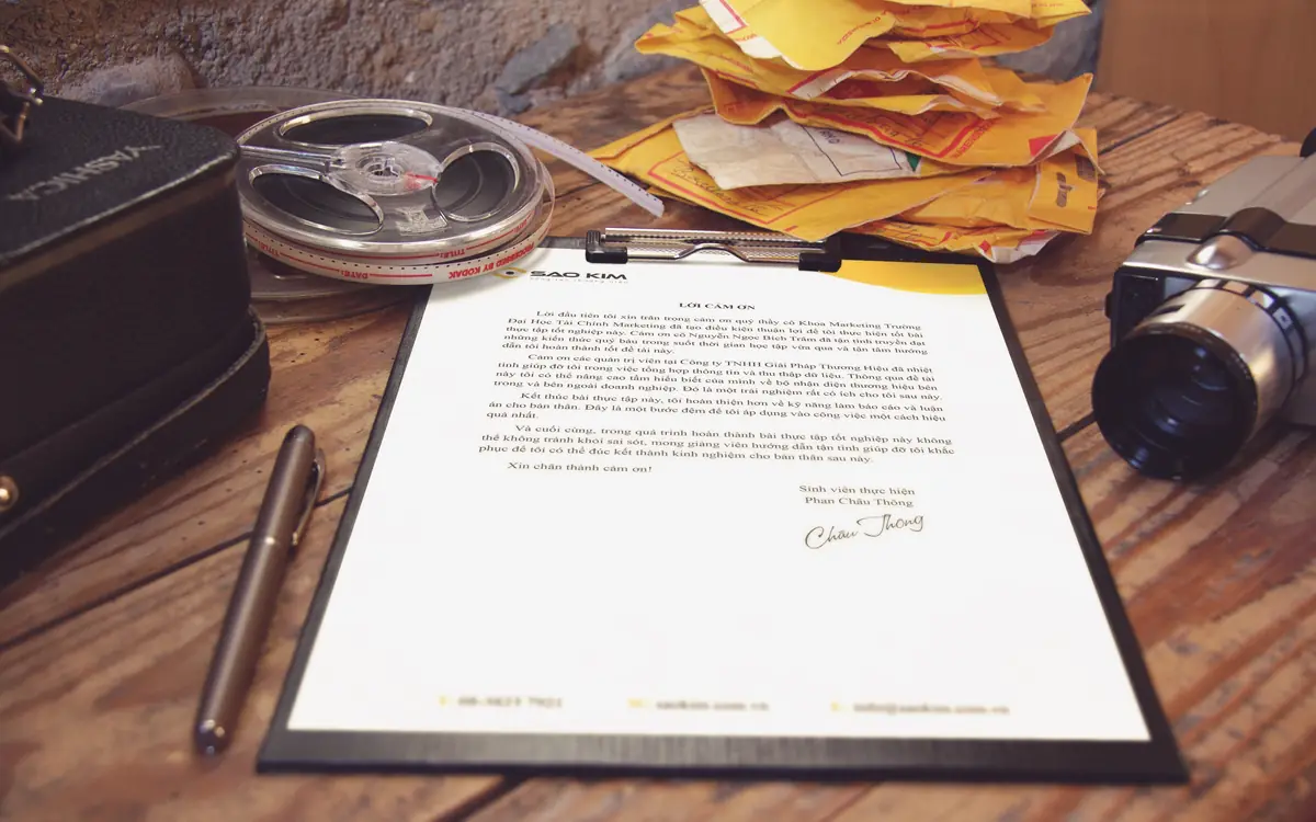 Contract papers and a pen on a wooden desk with office gadgets