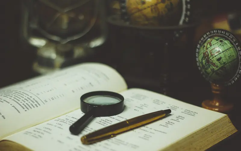 Magnifying glass and pen on an open book