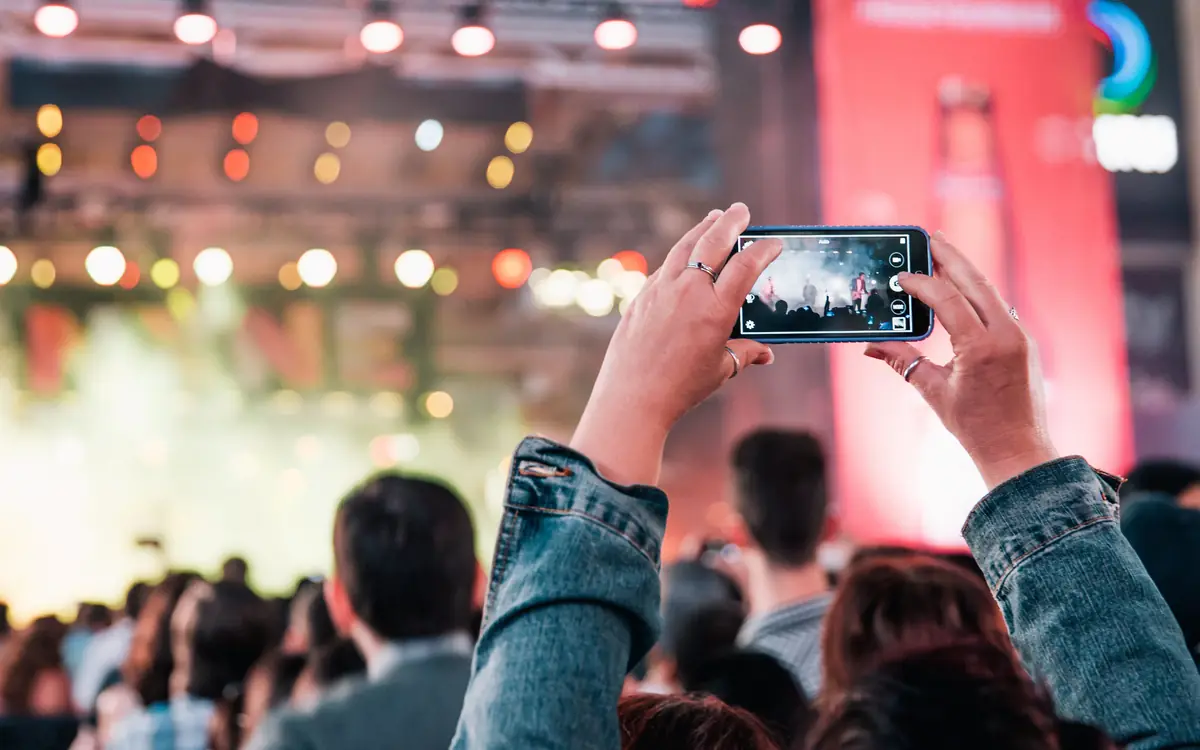 Concert crowd holding up phones to film the stage