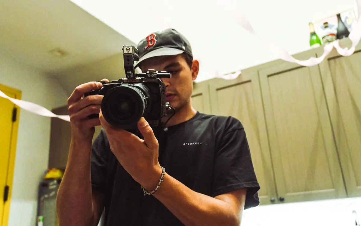 Videographer in a cap filming with a camera, seen from below