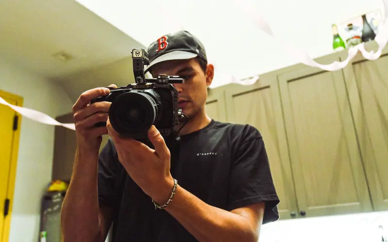 Videographer in a cap filming with a camera, seen from below